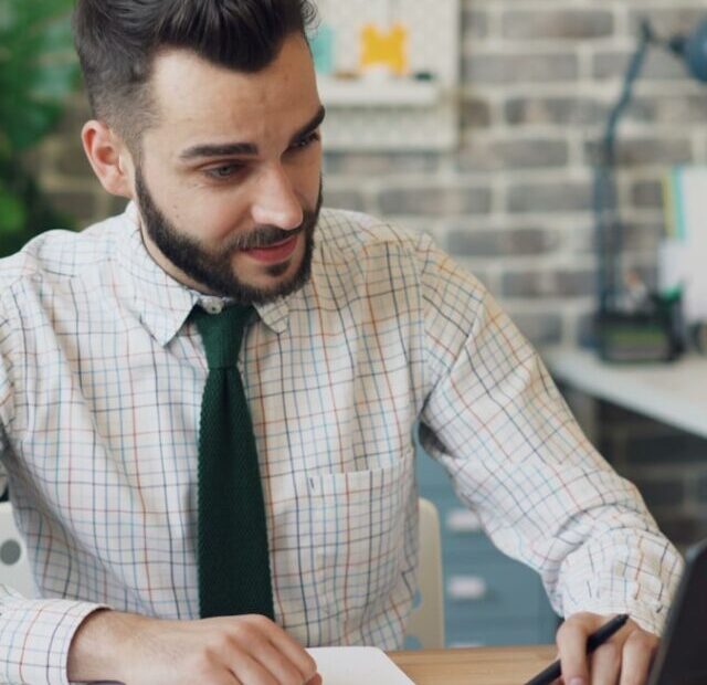 a man sitting at a desk working on a laptop