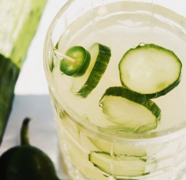 A glass of water with cucumber slices in it