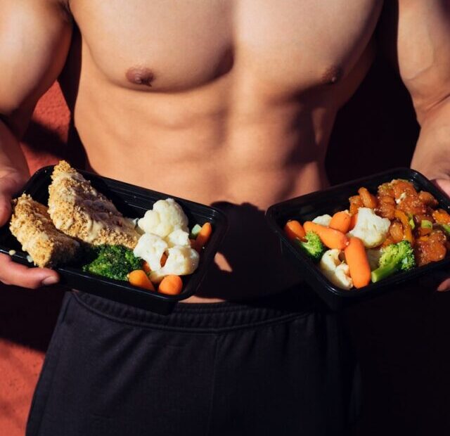 topless man in black shorts holding cooked food