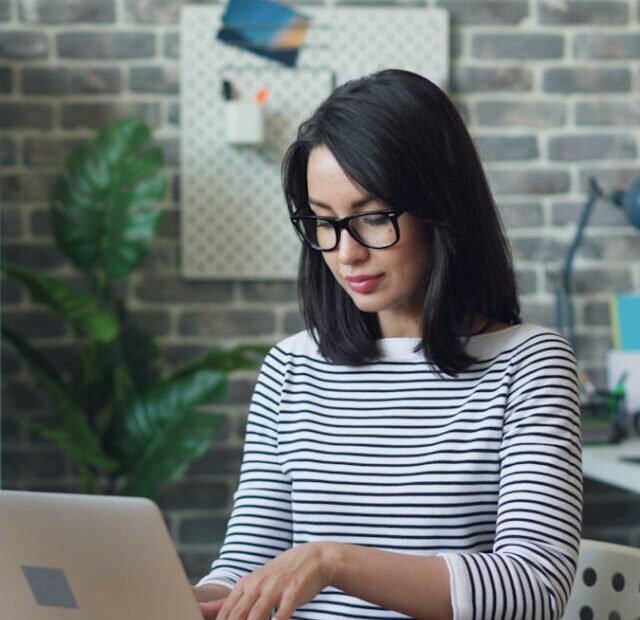 a woman sitting at a table using a laptop computer