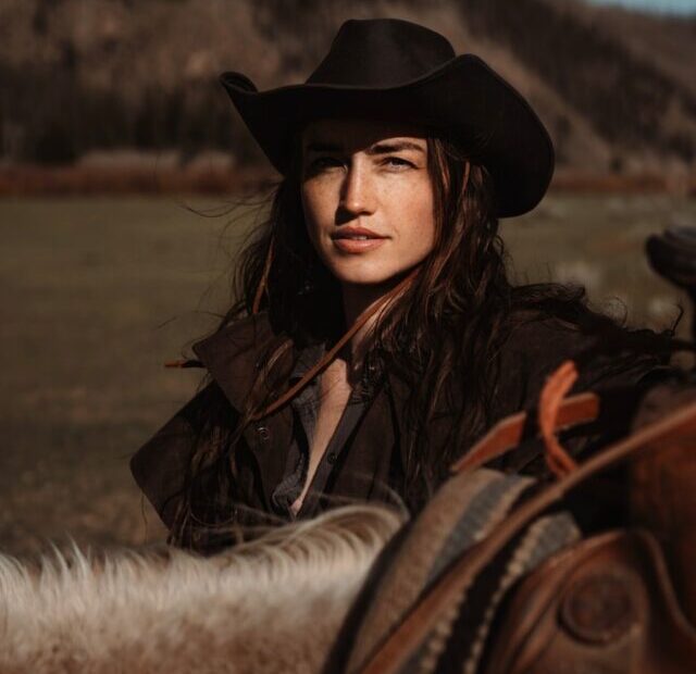 A woman in a cowboy hat riding a horse