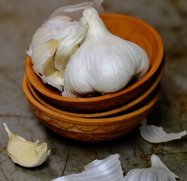 a wooden bowl filled with garlic on top of a counter