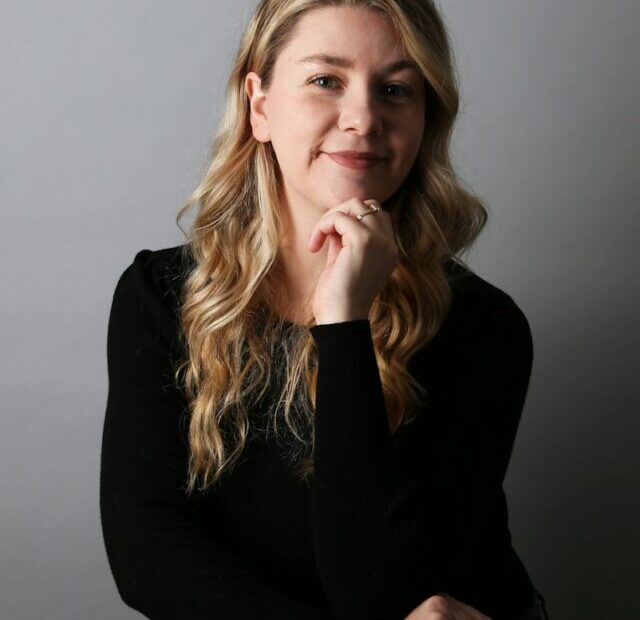 a woman sitting on a chair with her hand on her chin